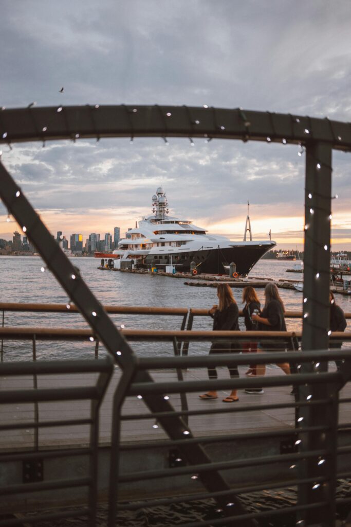 Scenic view of a luxury yacht at harbor with skyline backdrop during a vibrant sunset.