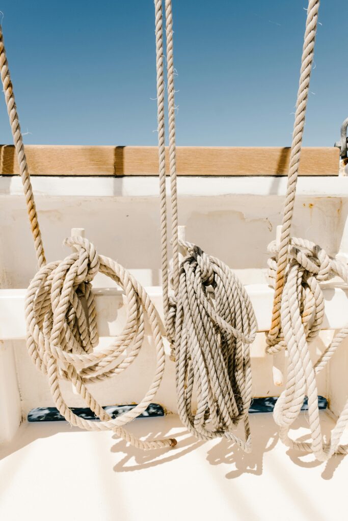 Close-up of nautical ropes hanging on a boat deck under clear blue sky.